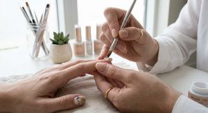 Technician applying a gel base before custom nail art detailing